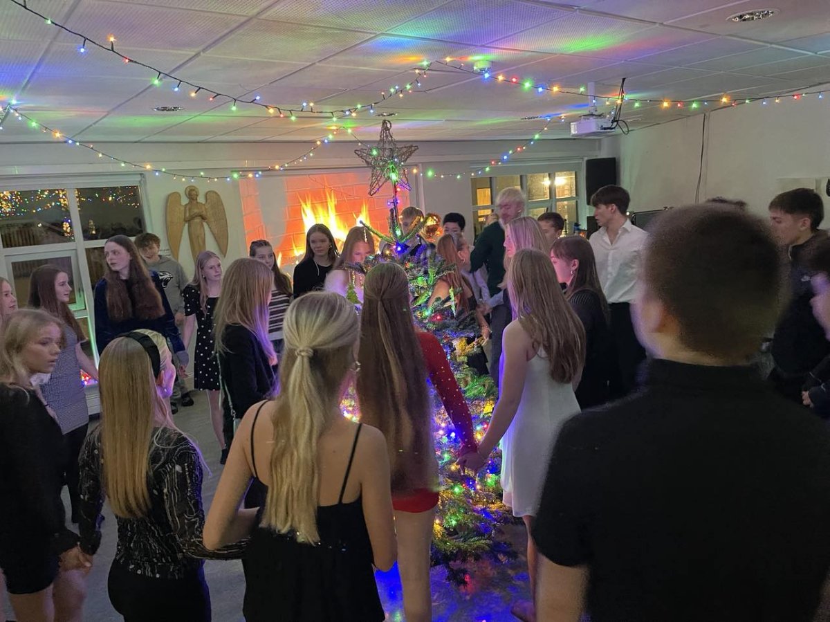 Unglingarnir dansa og syngja við jólatréð.